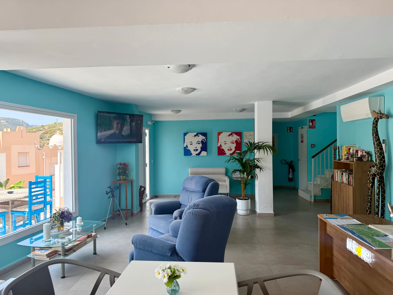 Recepción de Living One con paredes turquesa, butacas azules y retratos pop-art de Marilyn Monroe, el color de la marca viviendo en el edificio