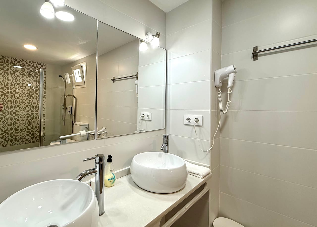 Baño con doble lavabo, gran espejo y pared de mosaico