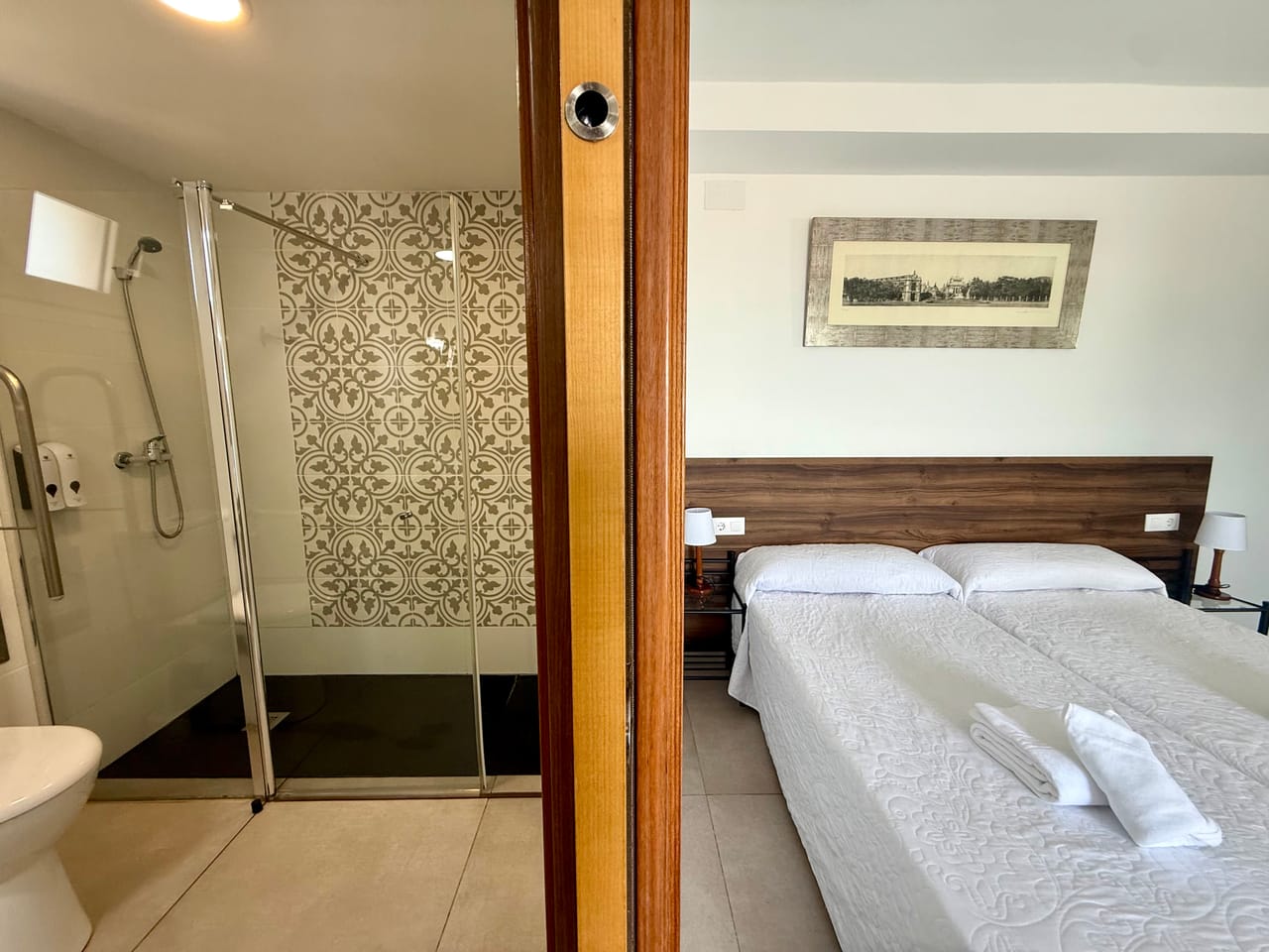 Ducha con mosaico decorativo y vista a la habitación a través de la puerta abierta