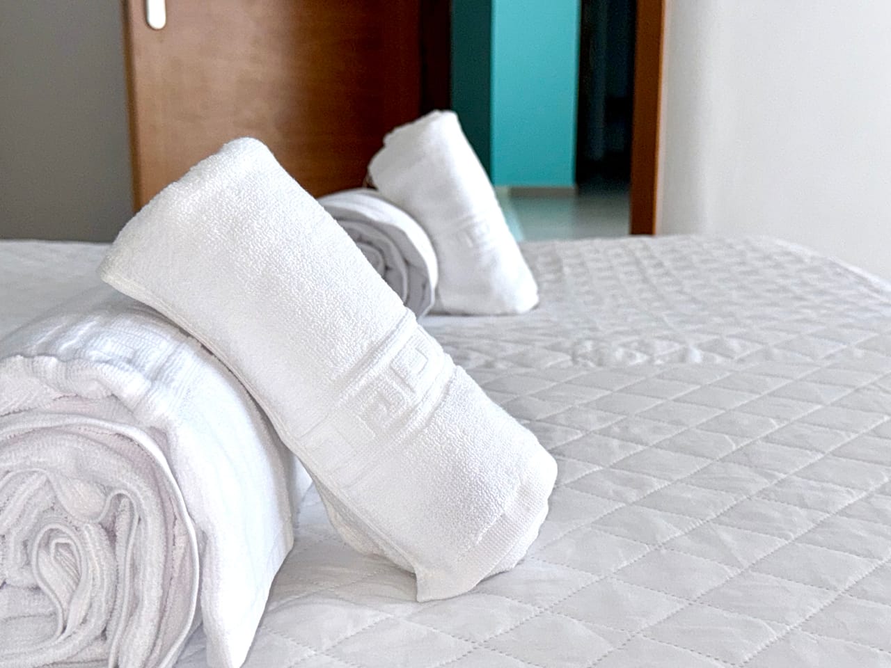 Primer plano de toallas blancas enrolladas sobre la cama, cada detalle cuenta