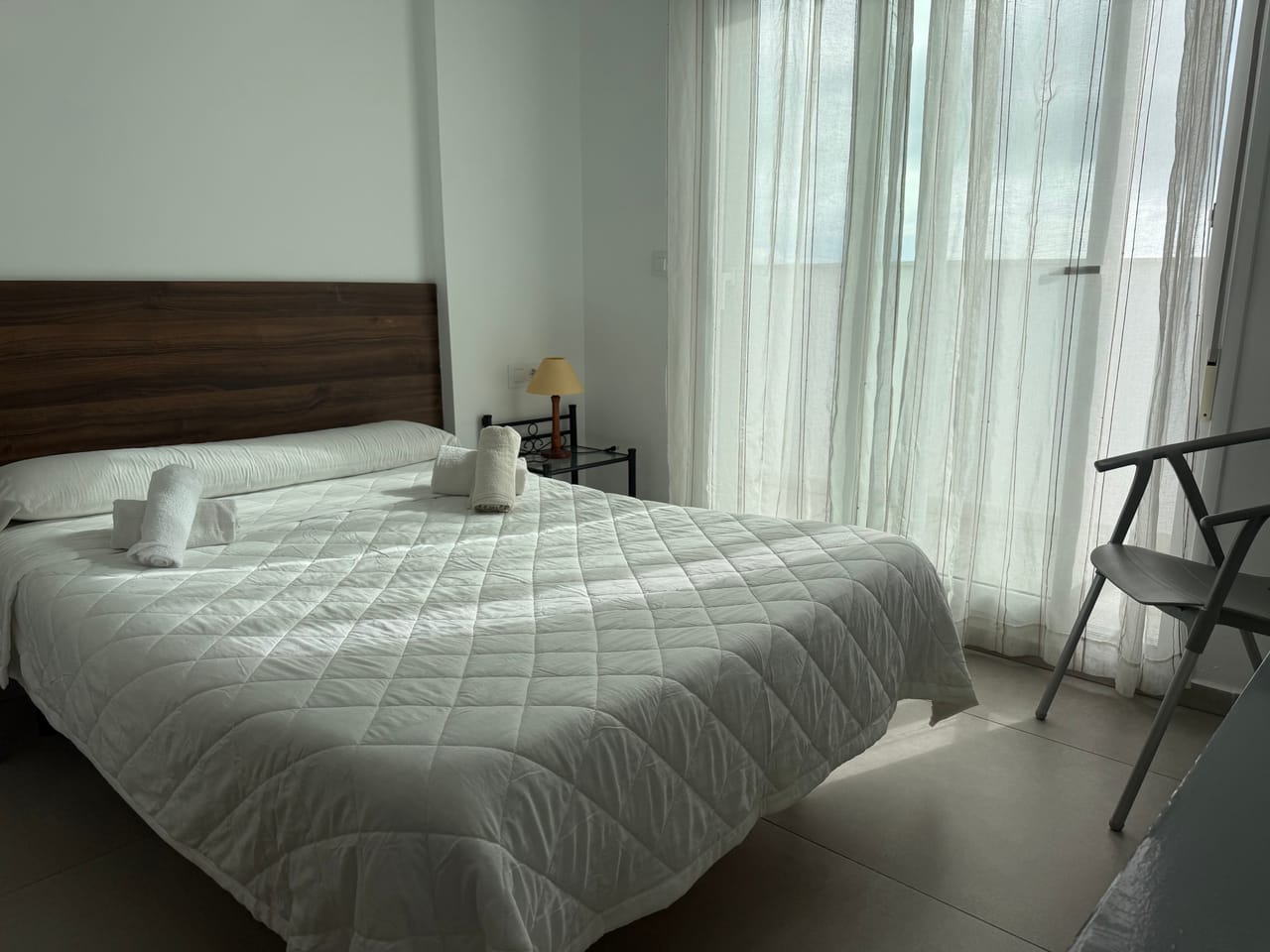 Habitación con cabecero de madera y luz filtrada por cortinas