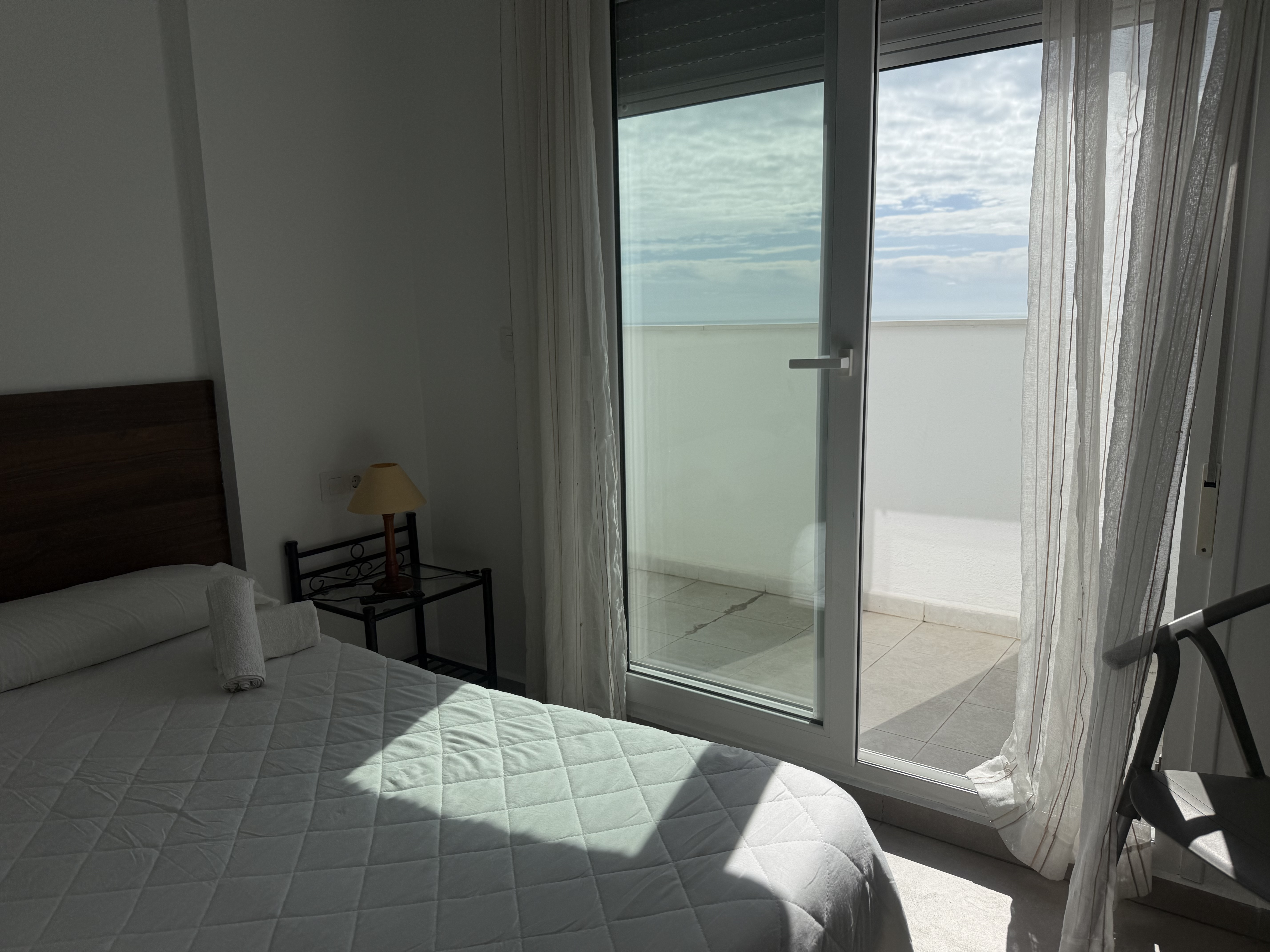 Habitación con puerta abierta a la terraza, cielo y horizonte de mar