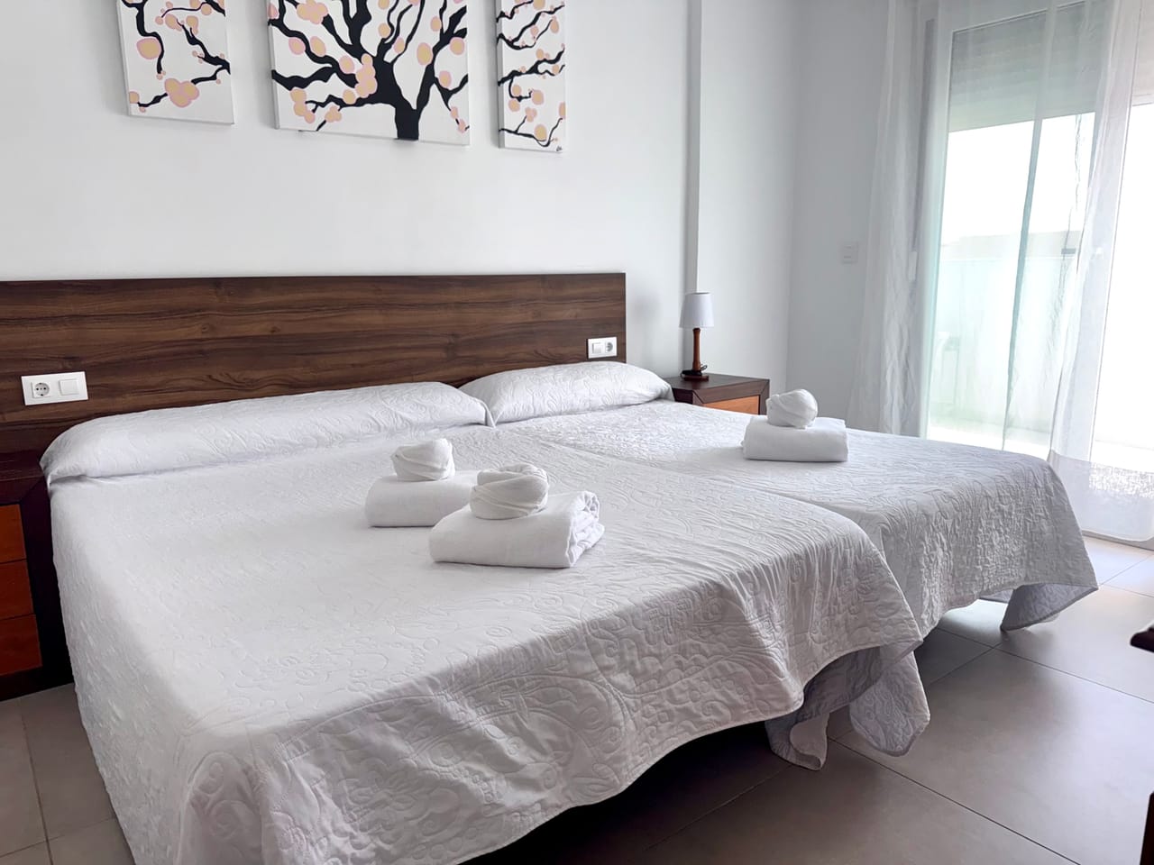 Habitación triple con tres camas y luz natural, ideal para familias o amigos