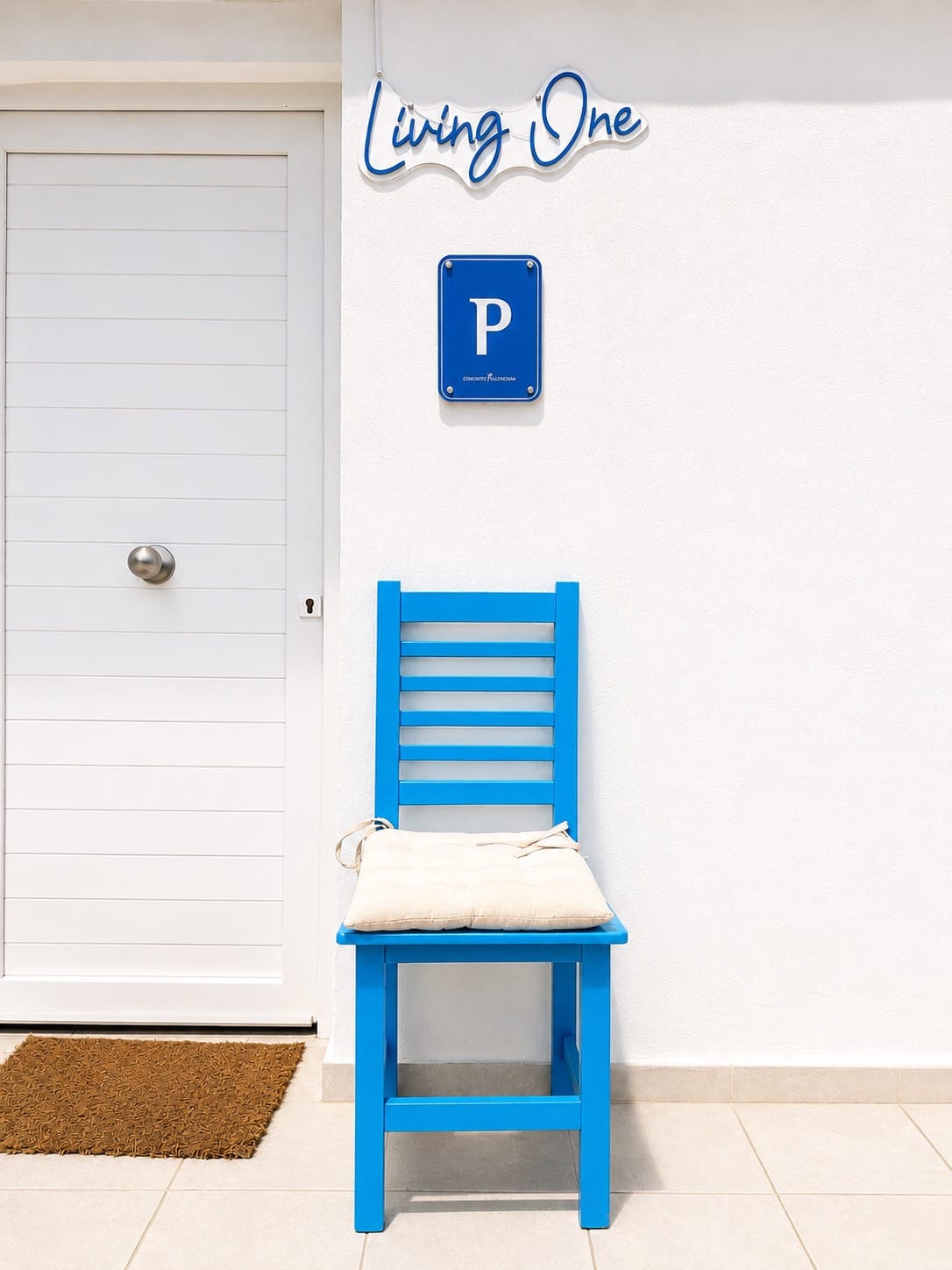 Entrada de Living One con el rótulo de la marca y una silla azul mediterránea junto a la puerta