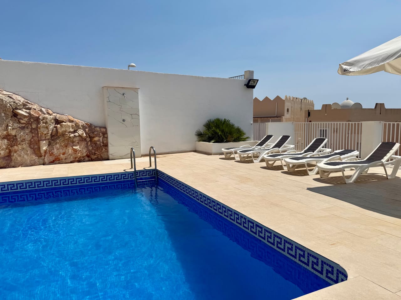 Piscina junto a la roca natural, con orla de mosaico de greca, el elemento diferencial de Living One